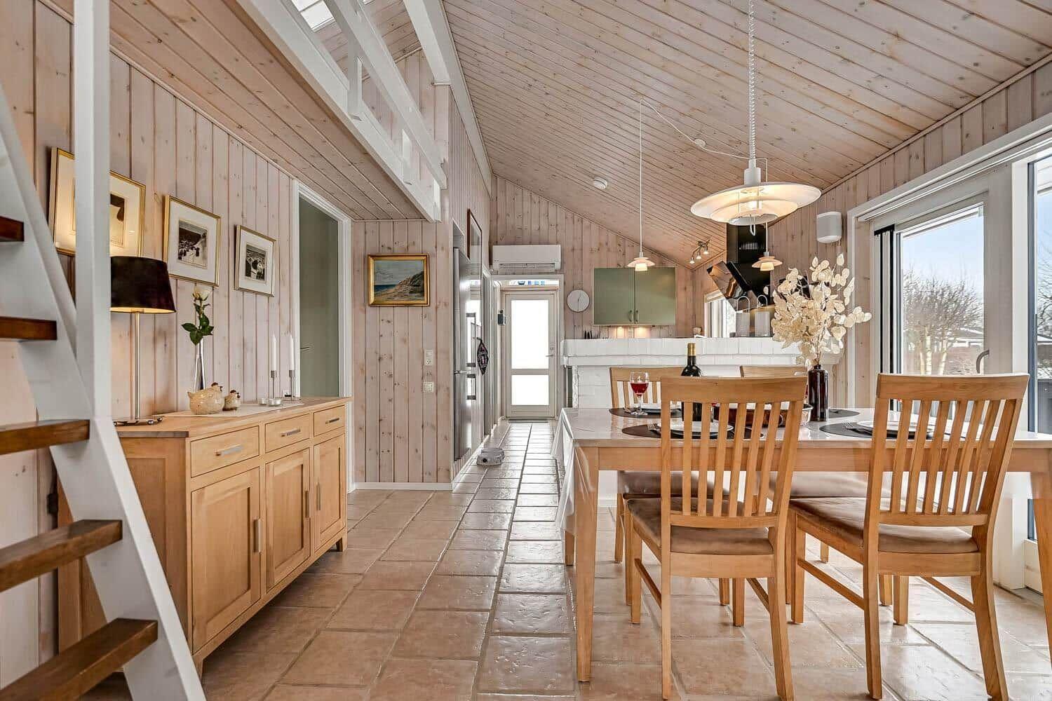 Essbereich mit Holztisch und Stühlen, Küche und Treppe zu einer oberen Etage.