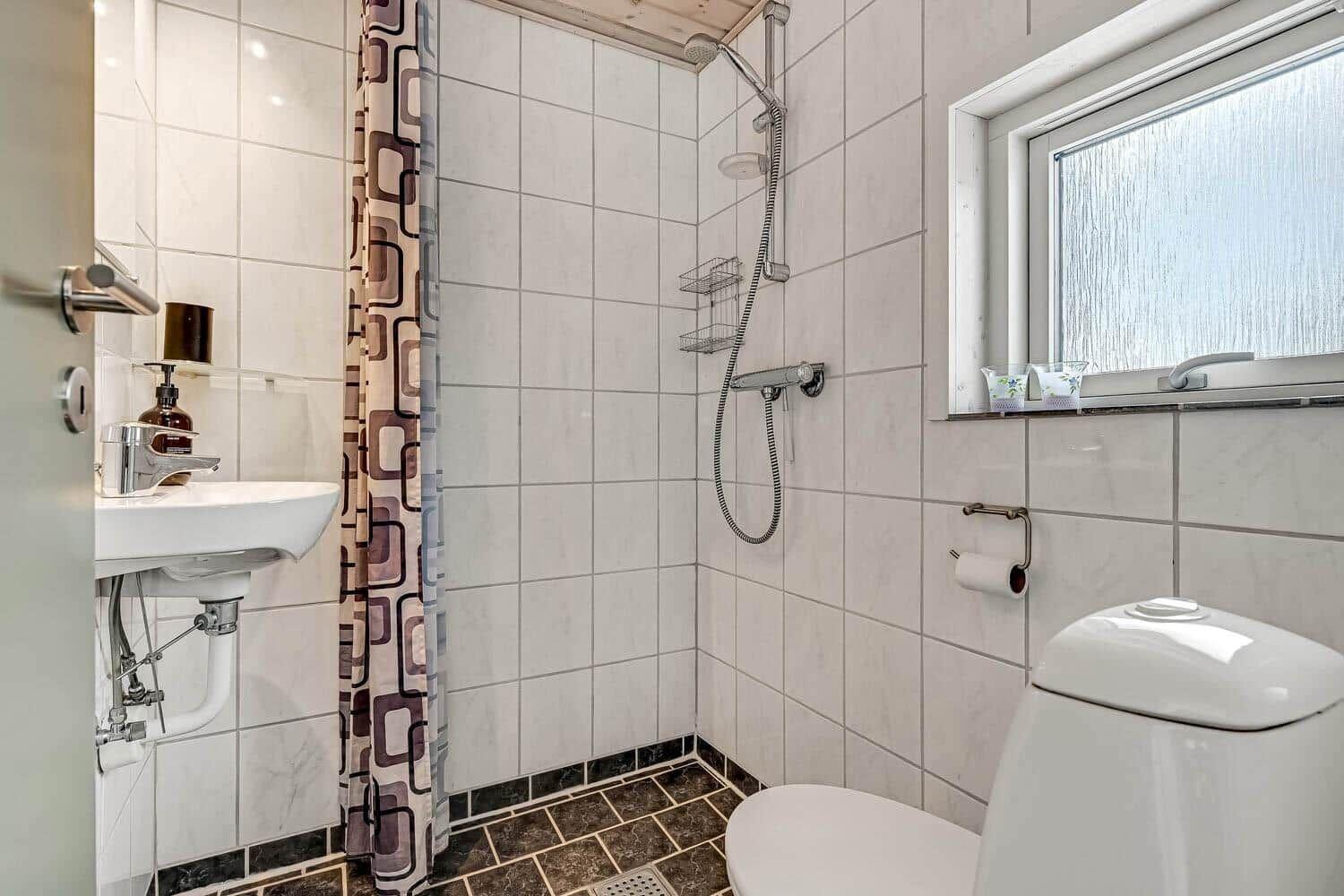 Badezimmer mit Dusche, Waschbecken und Toilette. Fenster mit Milchglas.