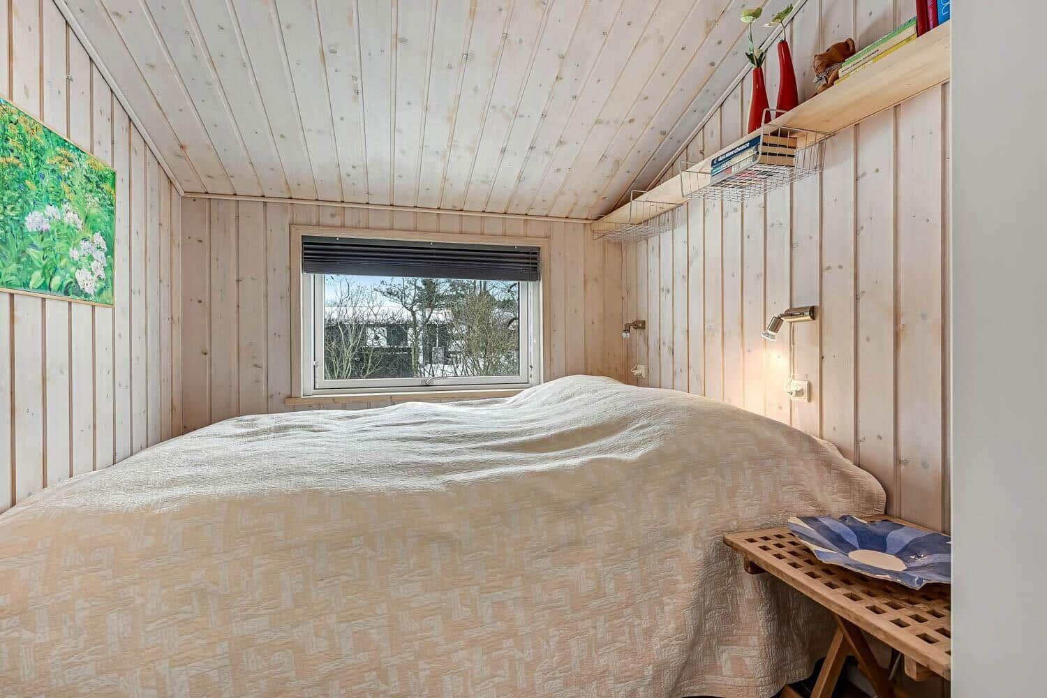 Schlafzimmer mit Holzwand, Bett und Fenster