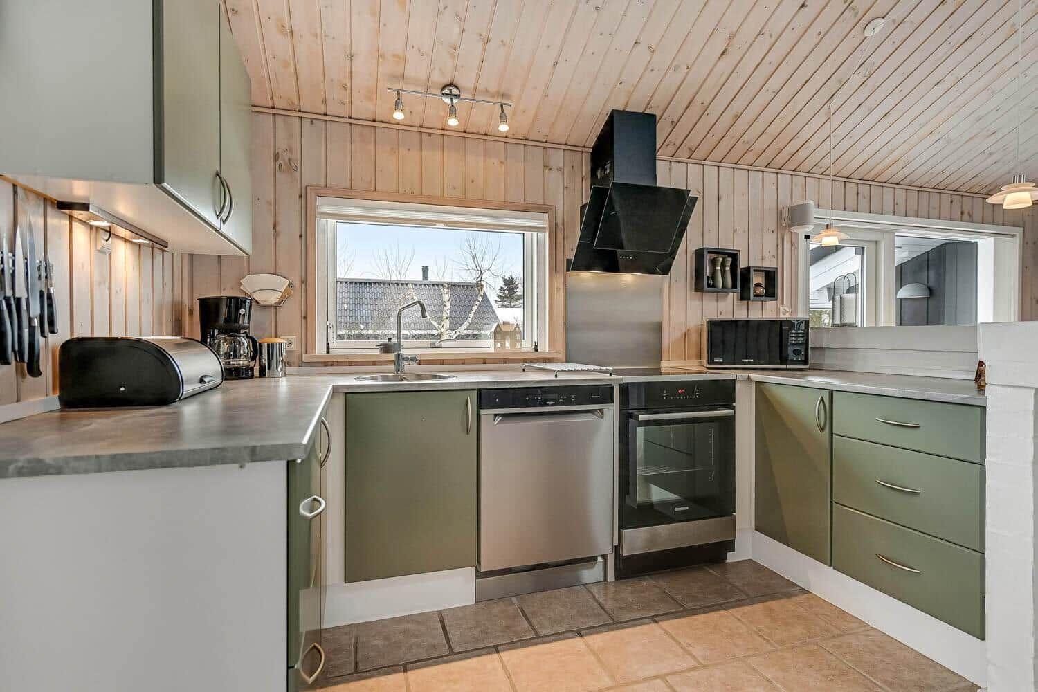 Küche mit Holzwand, Edelstahlgeräten und Fensterblick