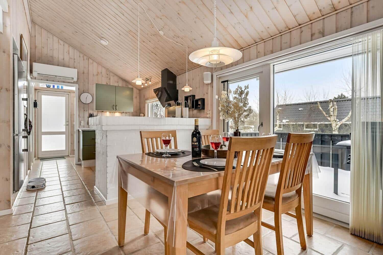 Essbereich mit Holztisch, Stühlen und Blick auf Balkon. Küche mit Arbeitsplatte und Küchenzeile.