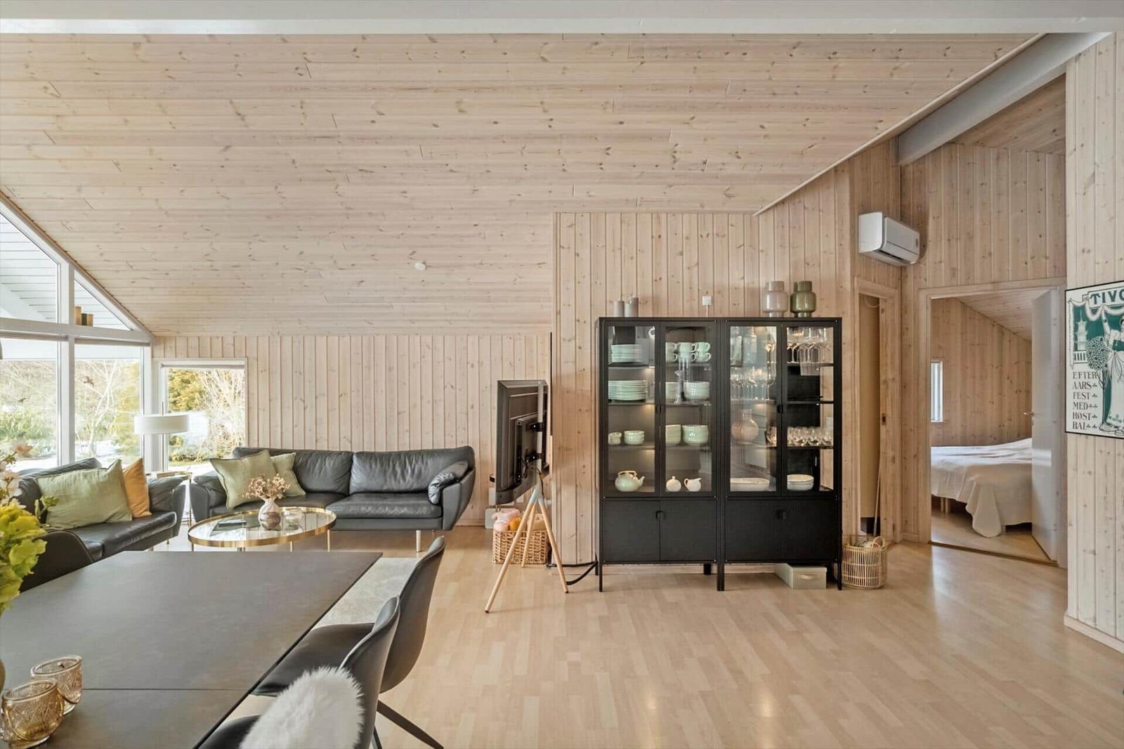 Living area with dining space, sofa, glass cabinet, and view into bedroom