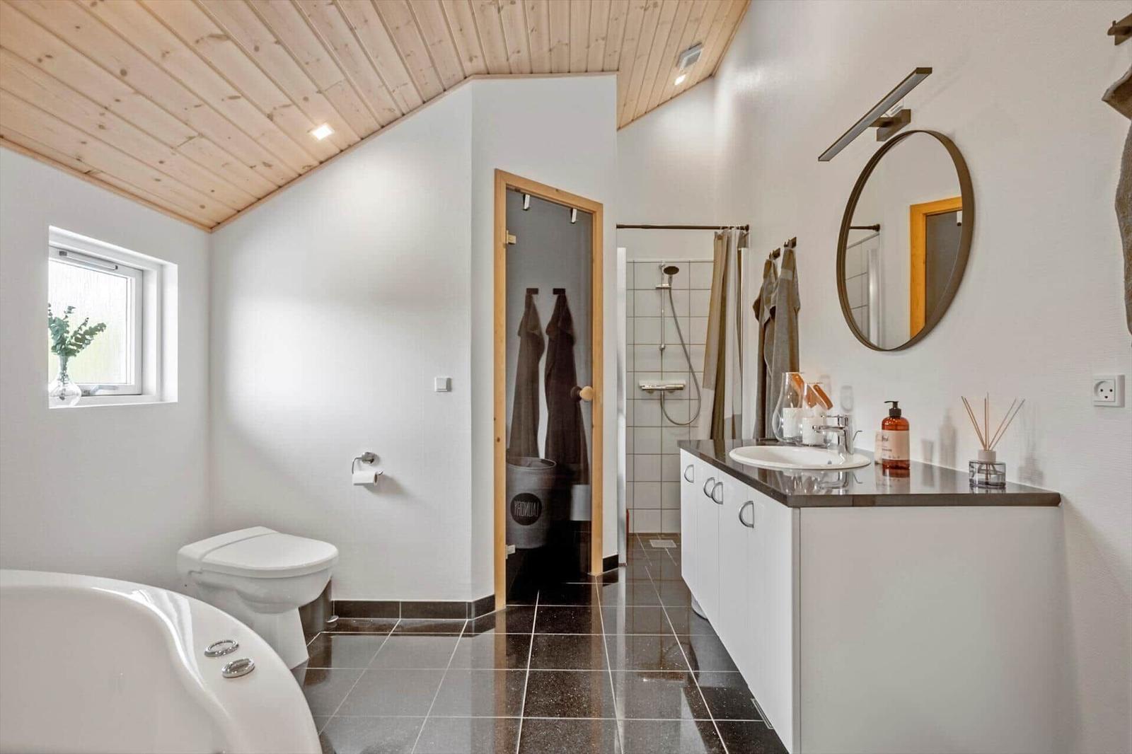 Bathroom with bathtub, toilet, shower, and sink with mirror.