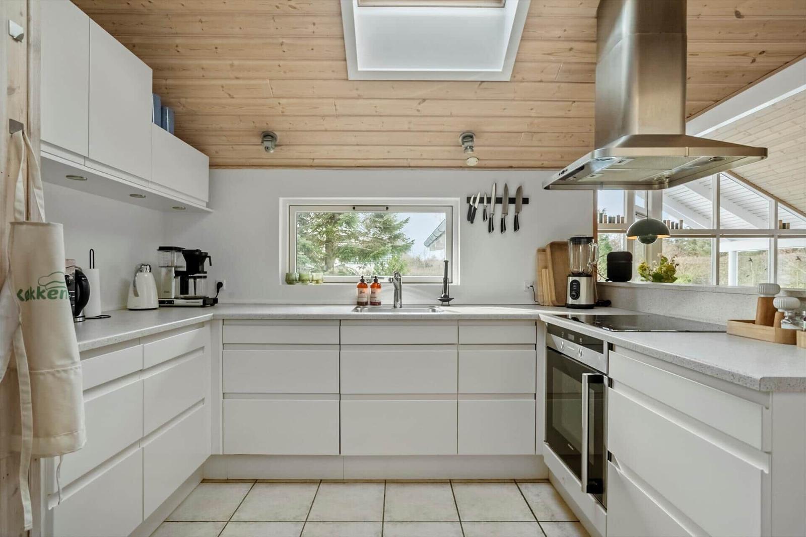 Modern kitchen with white cabinets, stainless steel stove, and skylight.