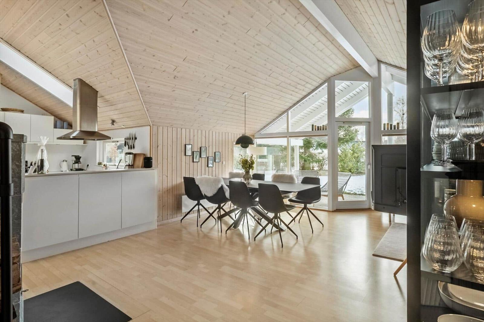 Kitchen and dining area with wooden floor and roof. Glass door leads to the terrace.