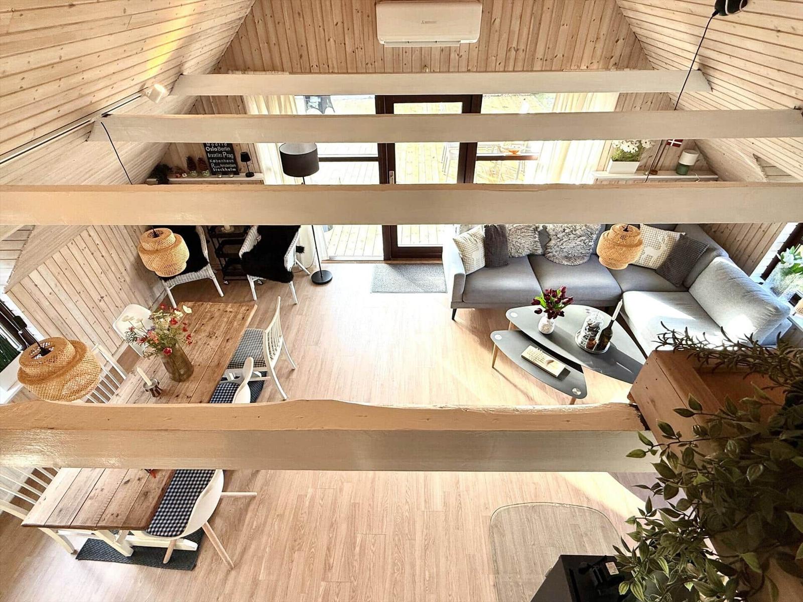 Wohnraum mit Sofa, Tisch und Stühlen unter Holzdecke