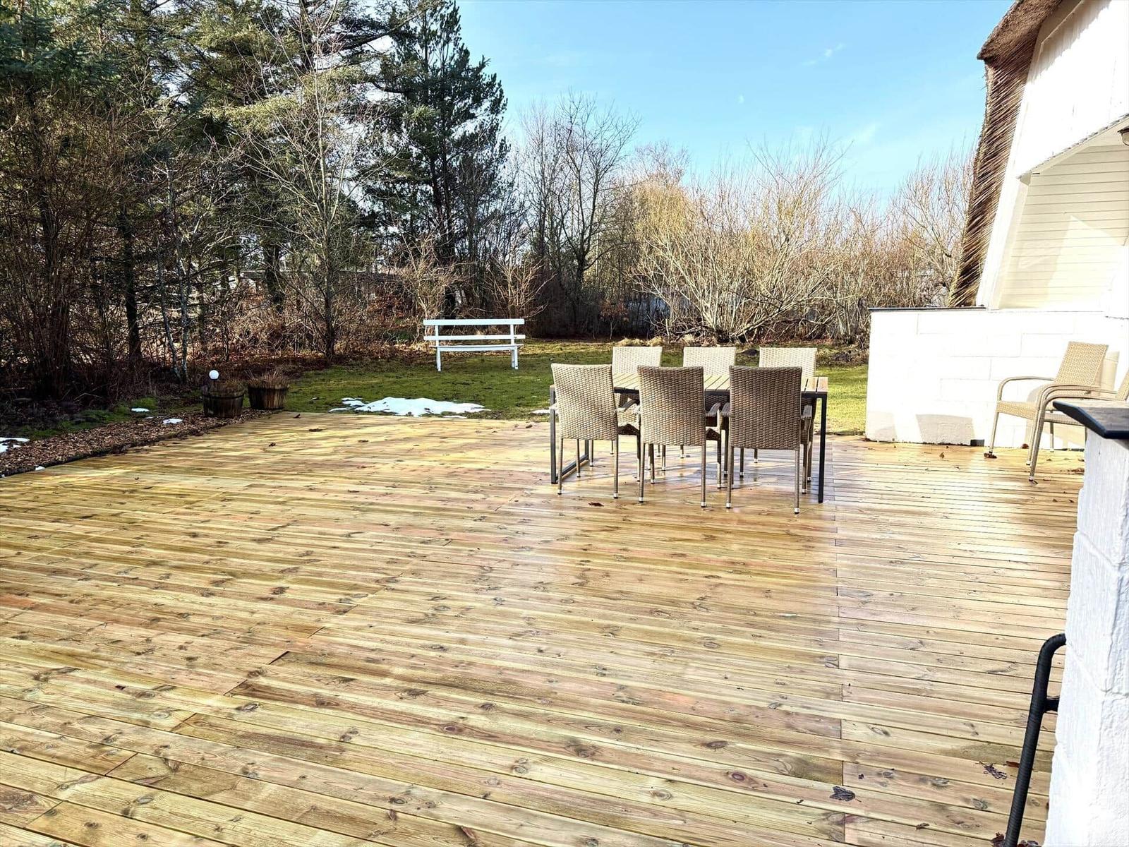 Holzterrasse mit Gartenmöbeln und Blick auf Wald.