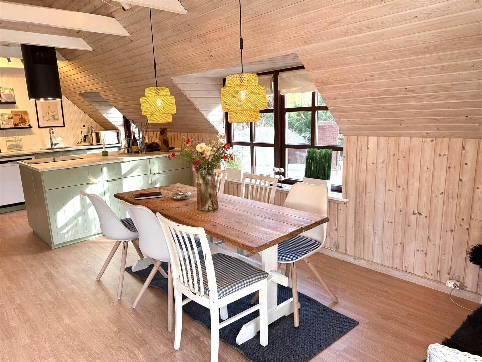 Essbereich mit Holztisch und Stühlen unter Holzdecke mit Fenster.