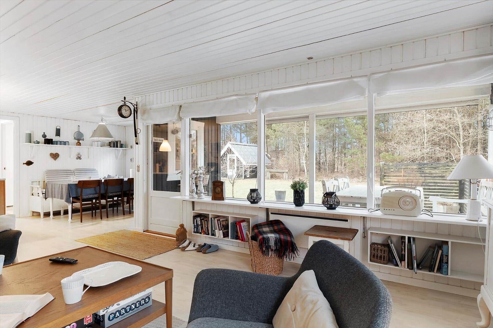 Living room with large window, sofa, and dining table in background.
