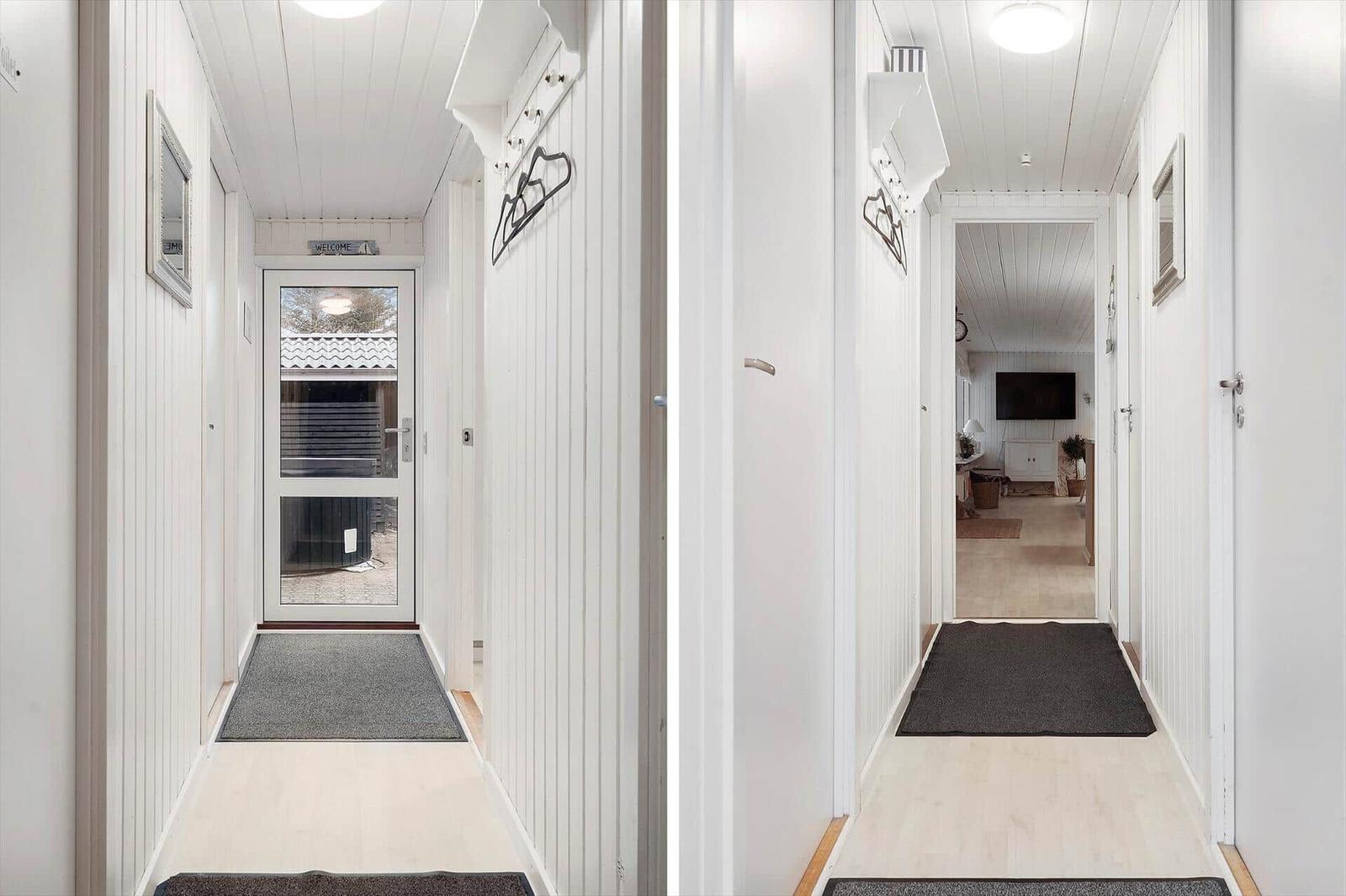 Entrance area with white walls and flooring. Door and hallway are visible.