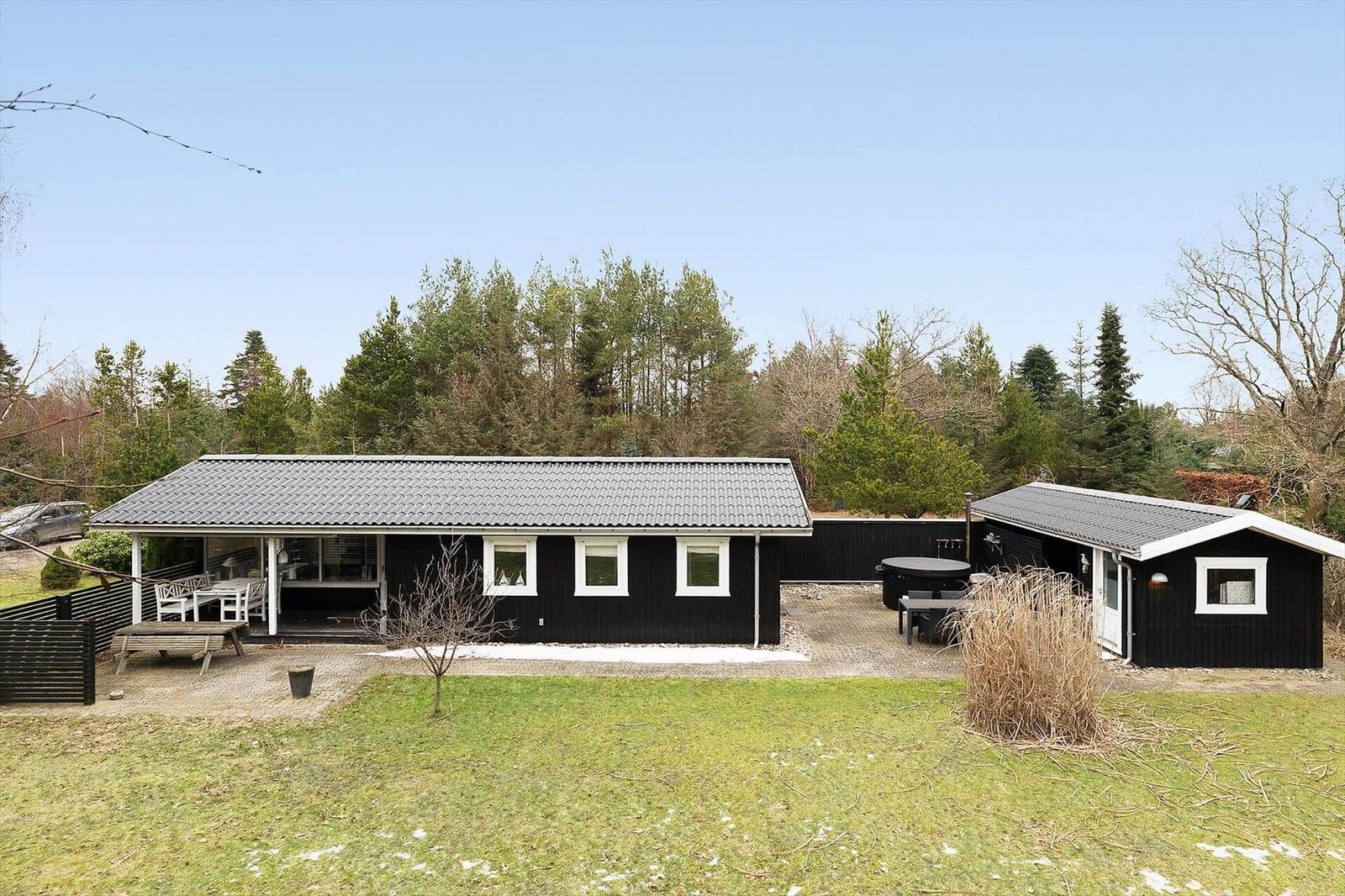 Black holiday house with terrace and garden. Attached building with barbecue area.