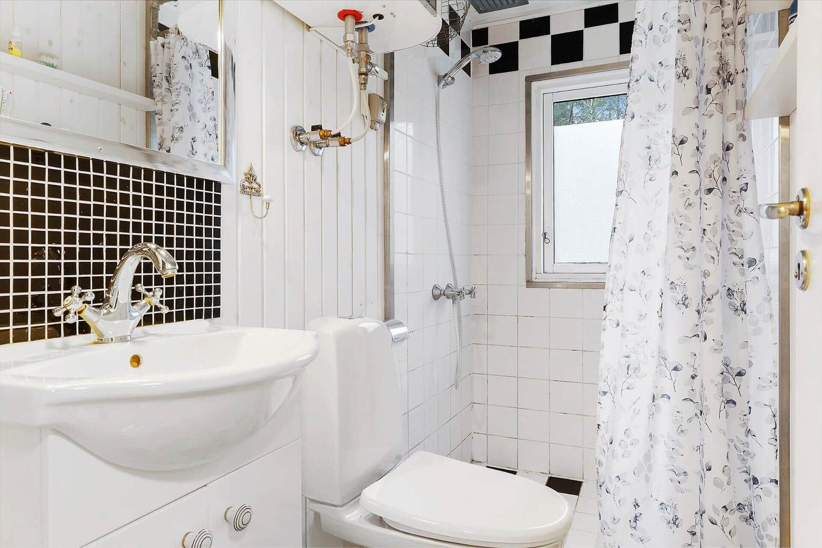 Bathroom with sink, toilet, and shower with window.