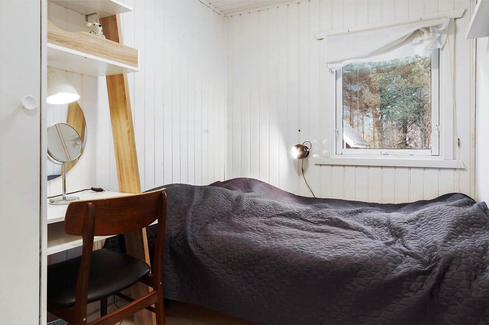 Bedroom with bed, desk, and window to the forest
