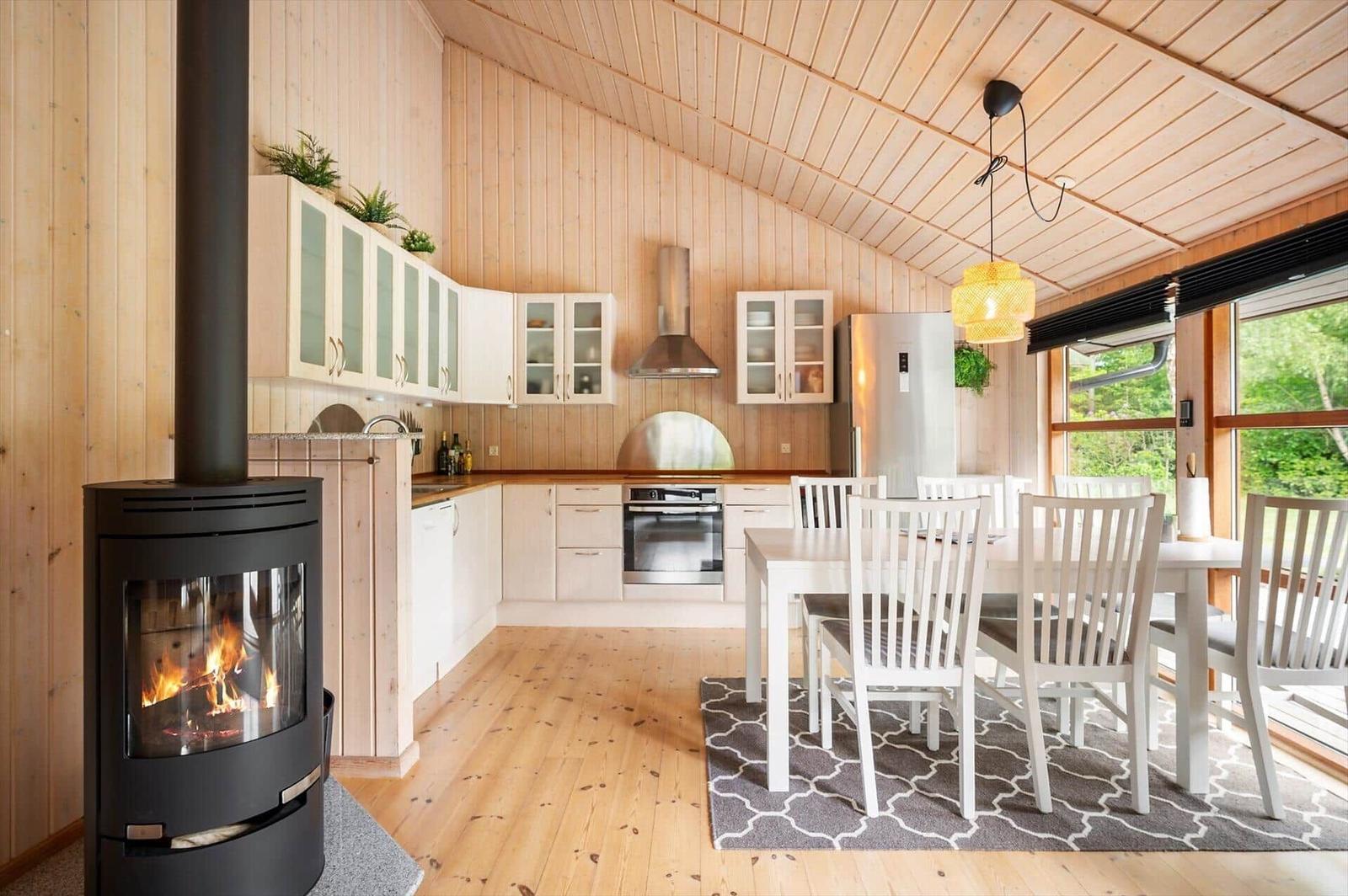 Küche mit Esstisch, Kamin und Holzwandverkleidung.