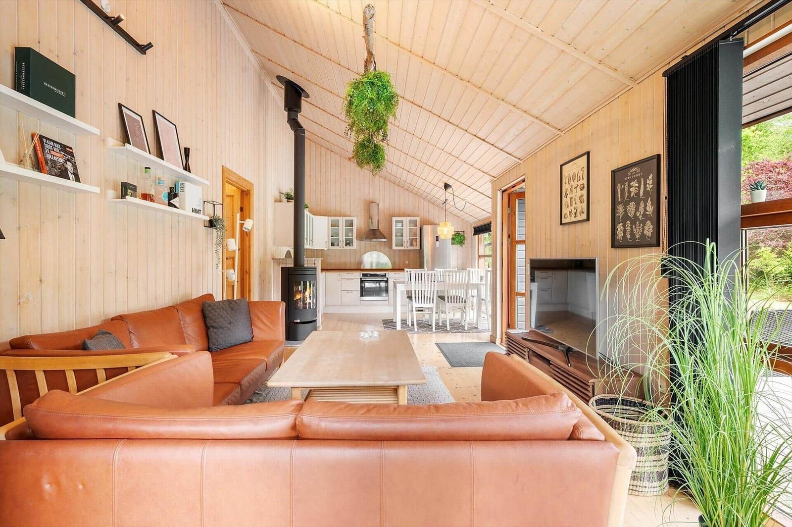 Wohnbereich mit Holzwand, Sofa, Kamin und Küchenbereich