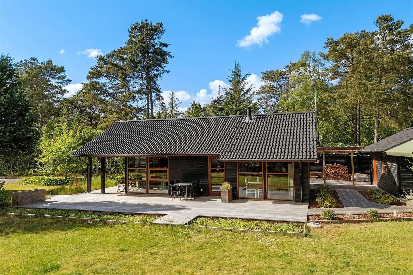 Modernes Haus mit Holzterrasse und Garten in Waldnähe.