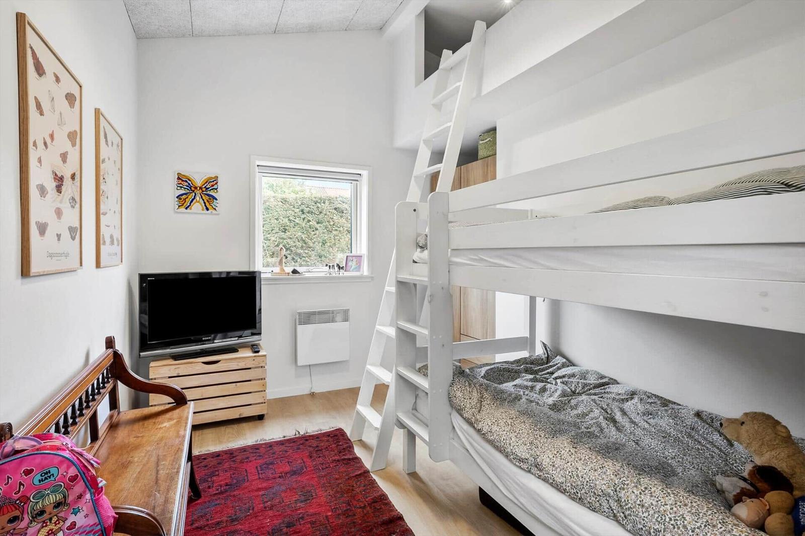 Kinderzimmer mit Doppelstockbett, Fernseher und Fenster.