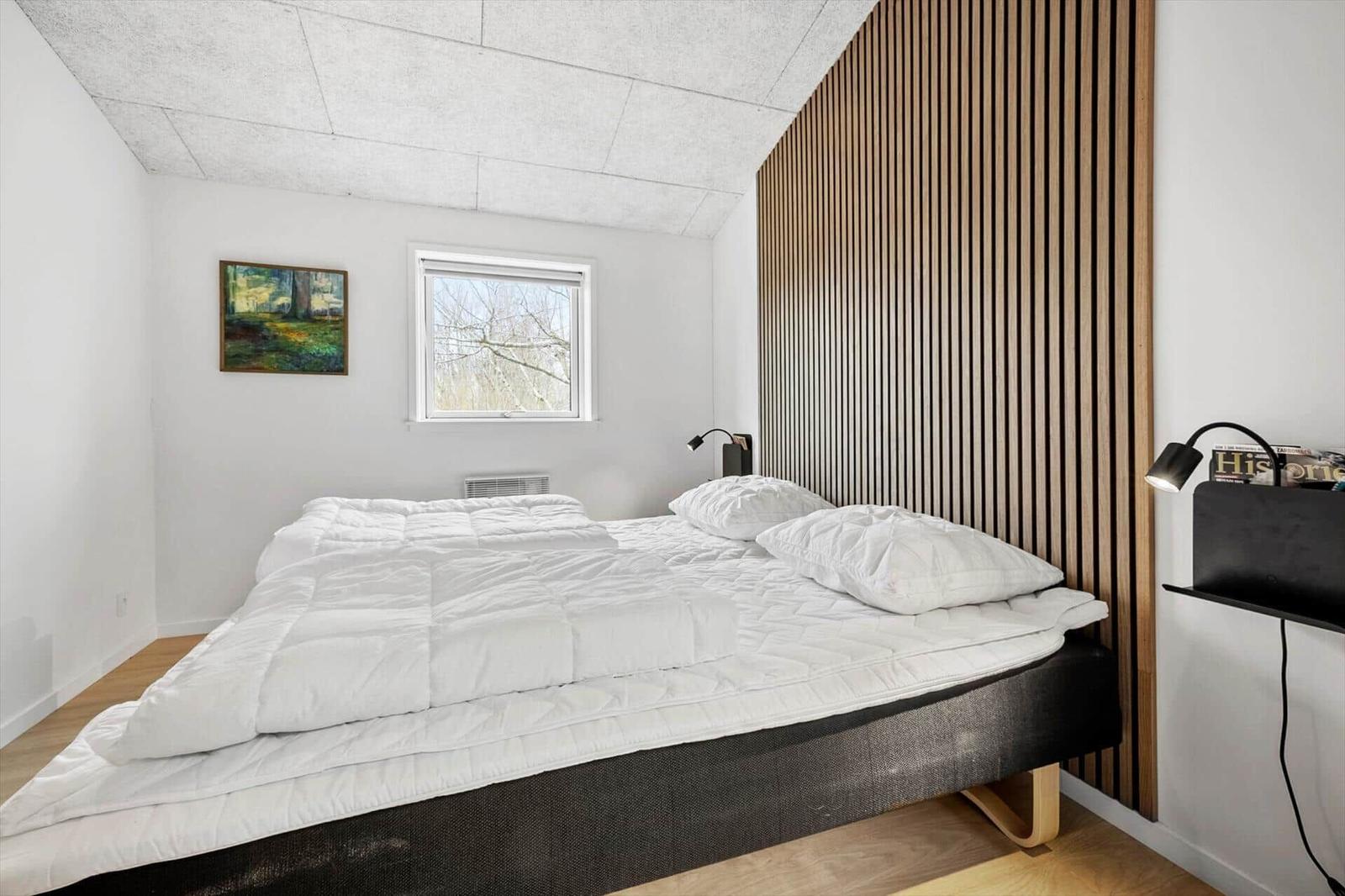 Schlafzimmer mit Bett, Fenster und Holzwand