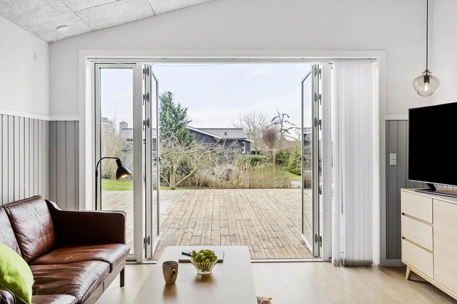 Wohnzimmer mit braunem Ledersofa und Blick auf Holzterrasse.