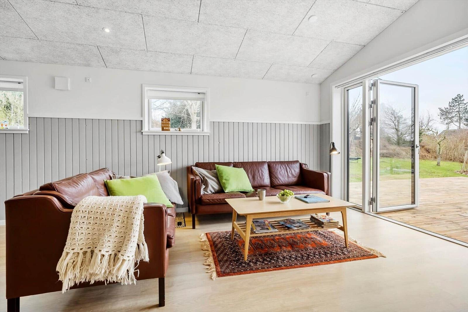 Wohnzimmer mit zwei Ledersofas, Holztisch und Terrassentür.