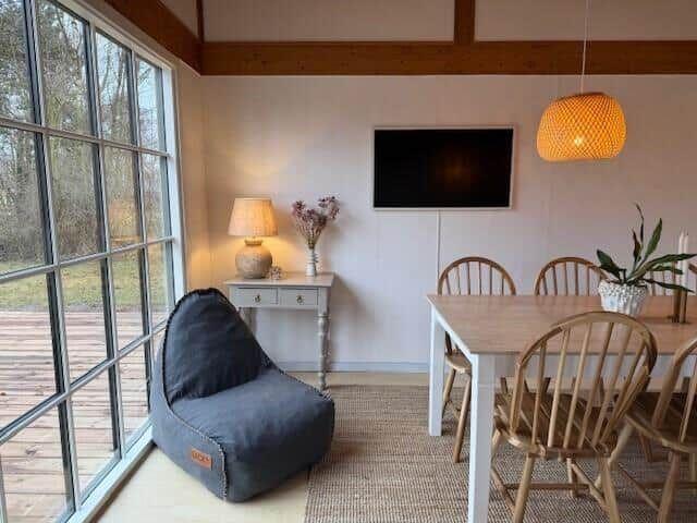 Essbereich mit Holztisch, Stühlen und Fernseher an der Wand.