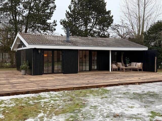 Moderne Holzhütte mit großem Balkon und Terrasse im Winter.