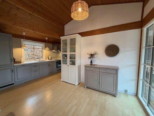 Küche mit Holzboden und -decke, weißen Schränken und Glasfronten.