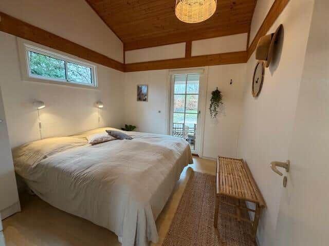 Schlafzimmer mit Doppelbett, Holzdecke und Fenster zur Terrasse.