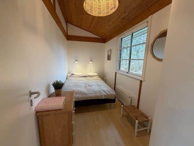 Schlafzimmer mit Bett, Schrank, Fenster und Deckenleuchte.