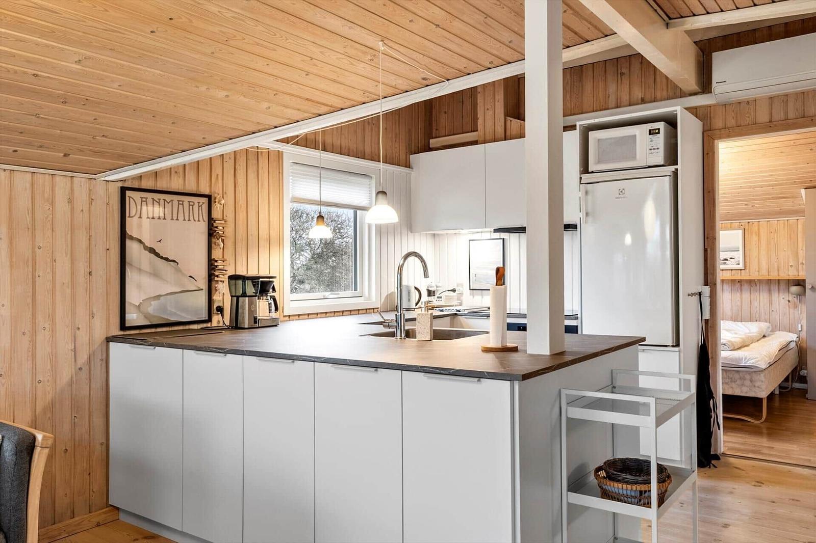 Kitchen with countertop, sink, and refrigerator. Bedroom visible in the background.