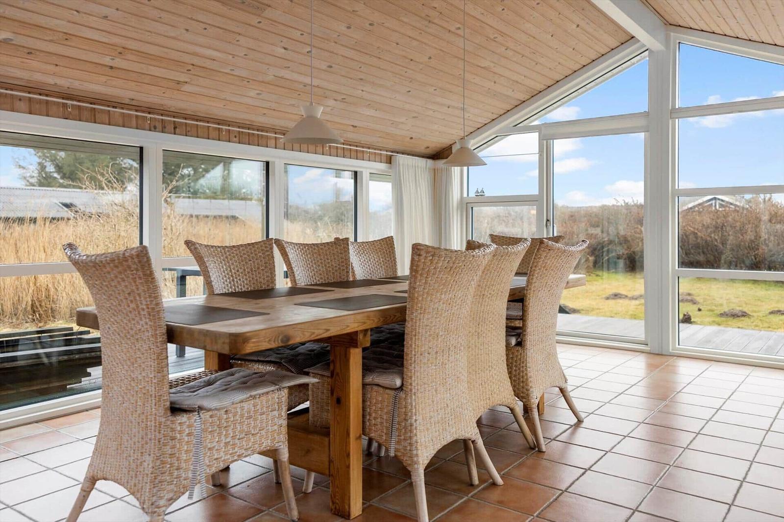 Dining room with wooden table, wicker chairs, and large window view.