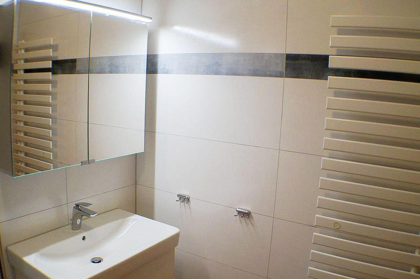 Badezimmer mit Waschbecken, Spiegelschrank und Heizkörper