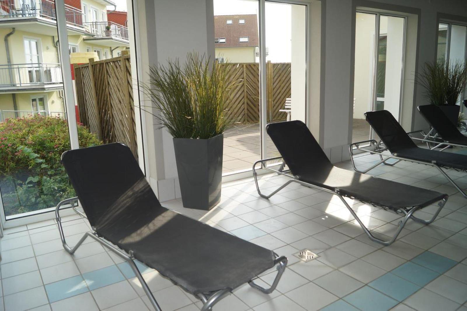 Terrasse mit Liegestühlen und Pflanzen. Durchgänge zu Außenbereich.