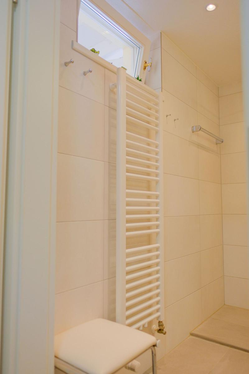 Badezimmer mit Dusche, Heizkörper und Fenster
