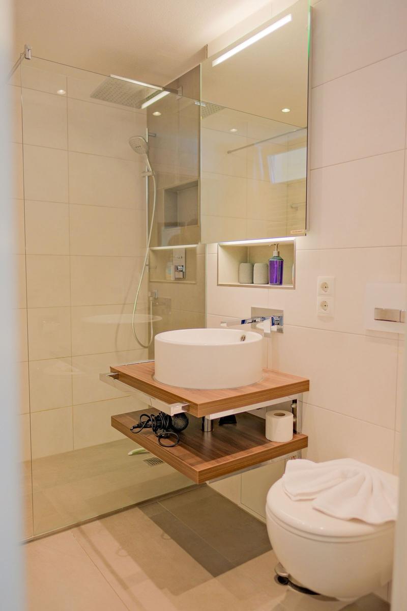 Badezimmer mit Dusche, Waschtisch und Toilette.