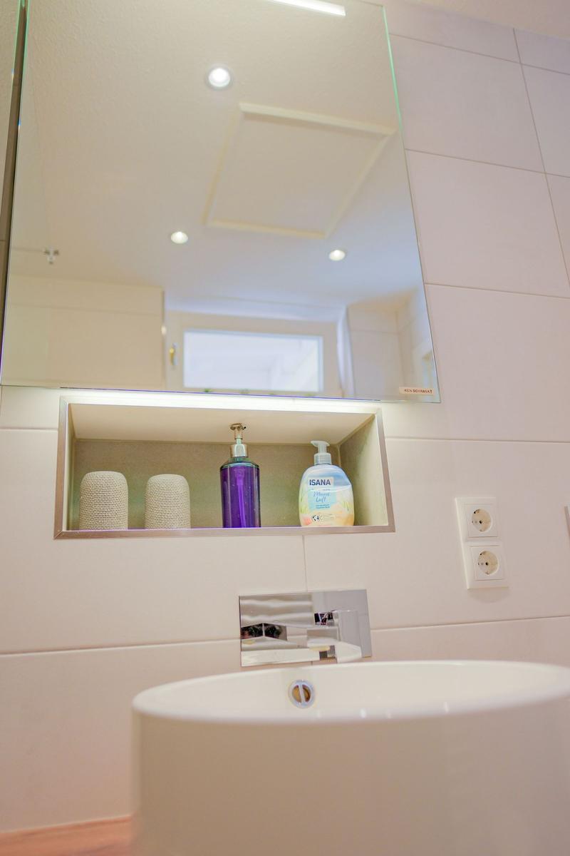 Badezimmer mit Spiegel, Waschbecken und Aufbewahrungsfach