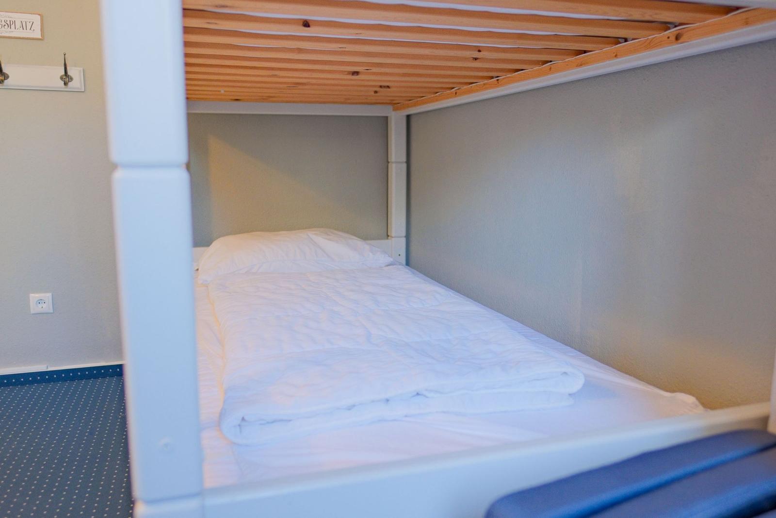 Unterbett mit weißer Bettwäsche und Holzdecke
