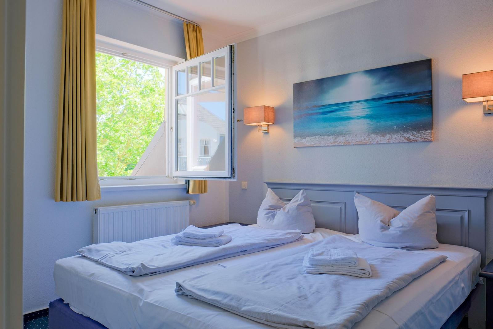 Ein Schlafzimmer mit Bett, Fenster und Wandbild.