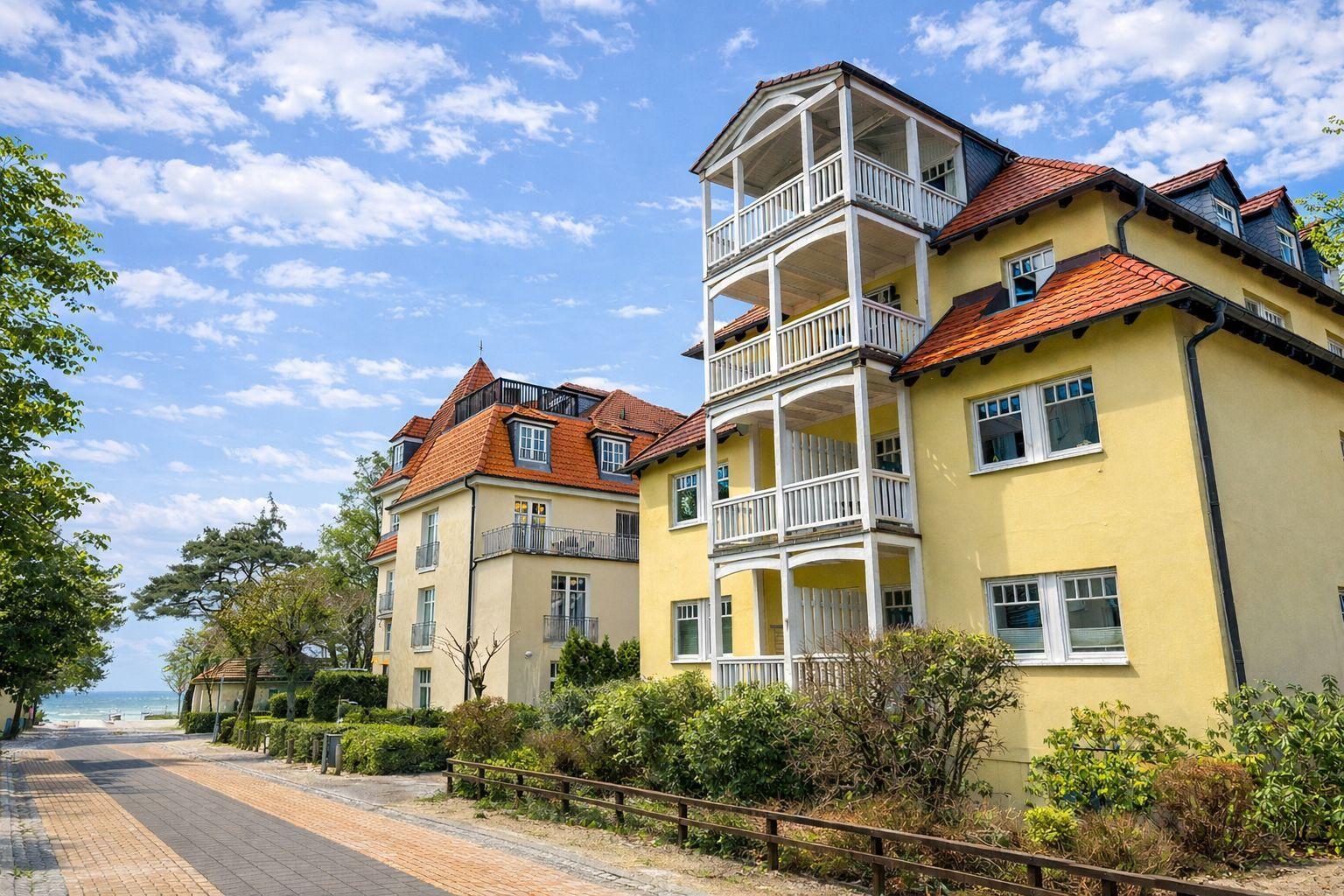 Hochhäuser mit Balkonen und roten Dächern an einer Straße mit Blick aufs Meer.