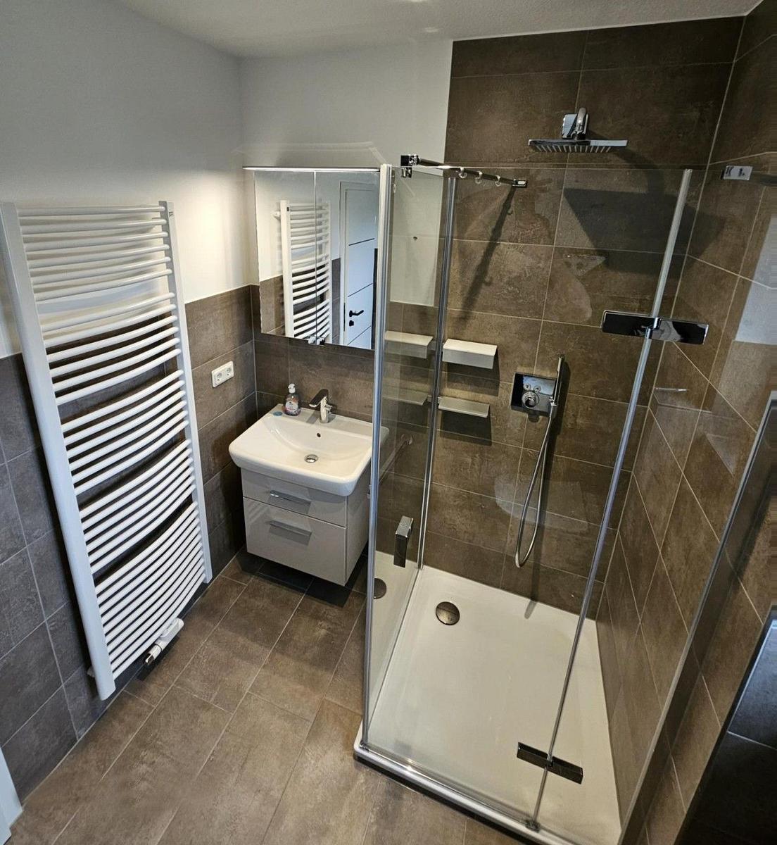 Bad mit Dusche, Waschbecken und Heizkörper