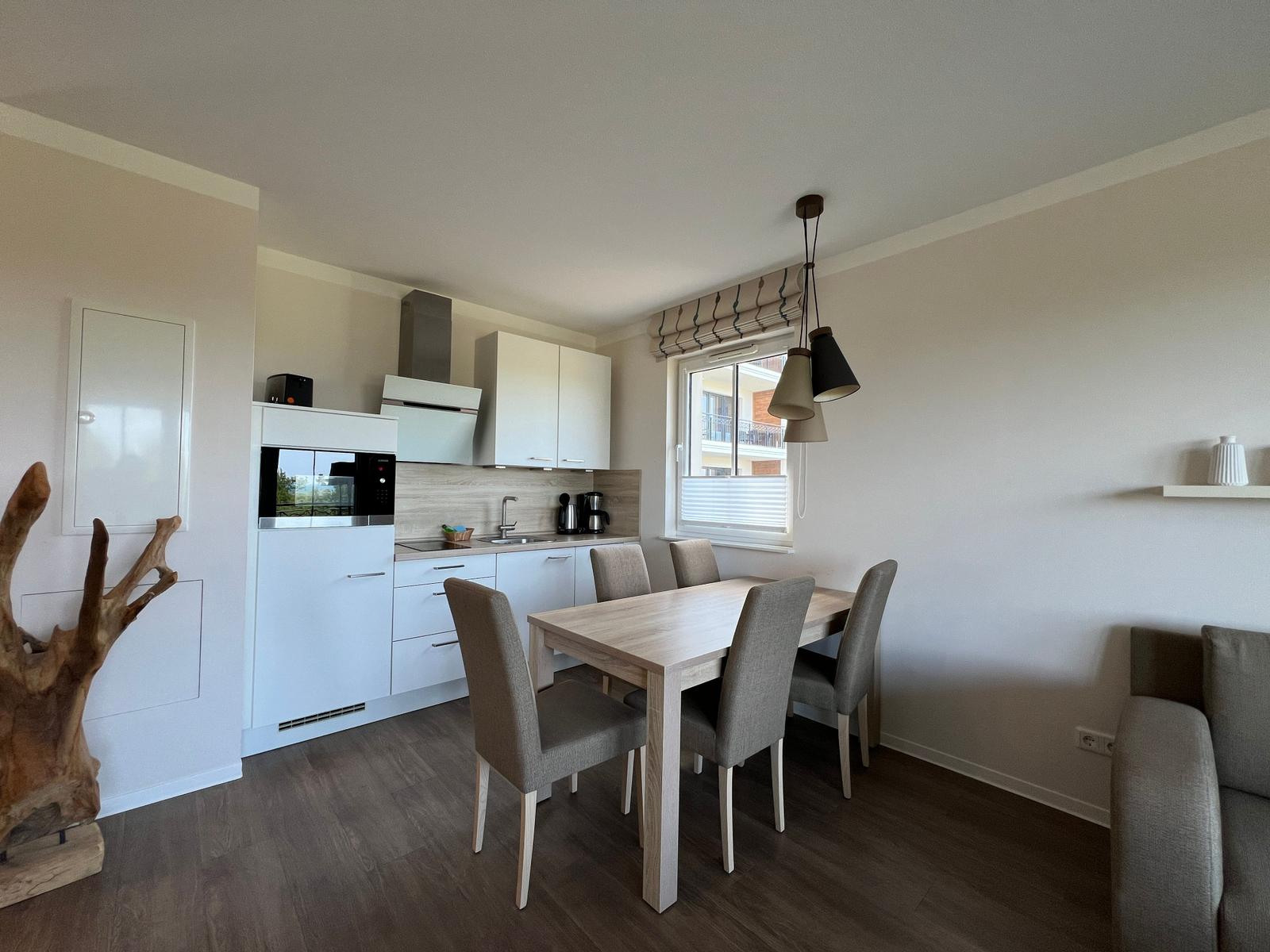 Küche mit Esstisch, Fenster und Wohnbereich mit Sofa.