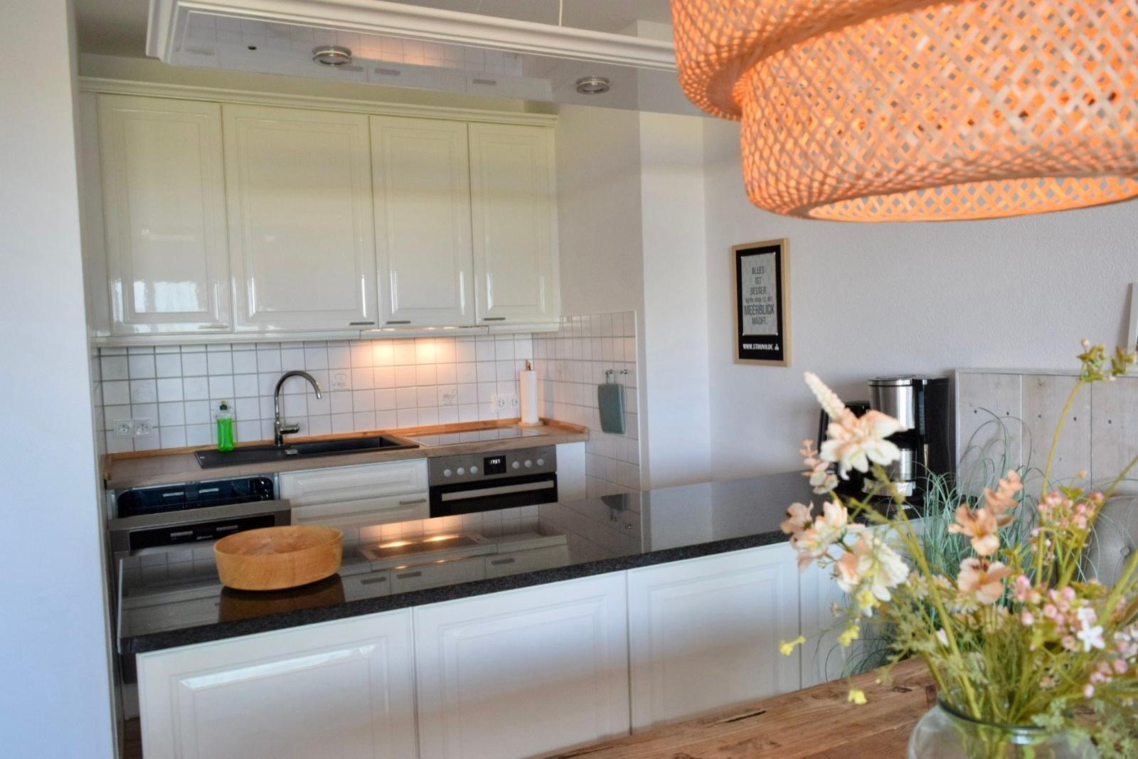 Küche mit weißen Schränken, Edelstahlgeräten und Holzoberflächen.