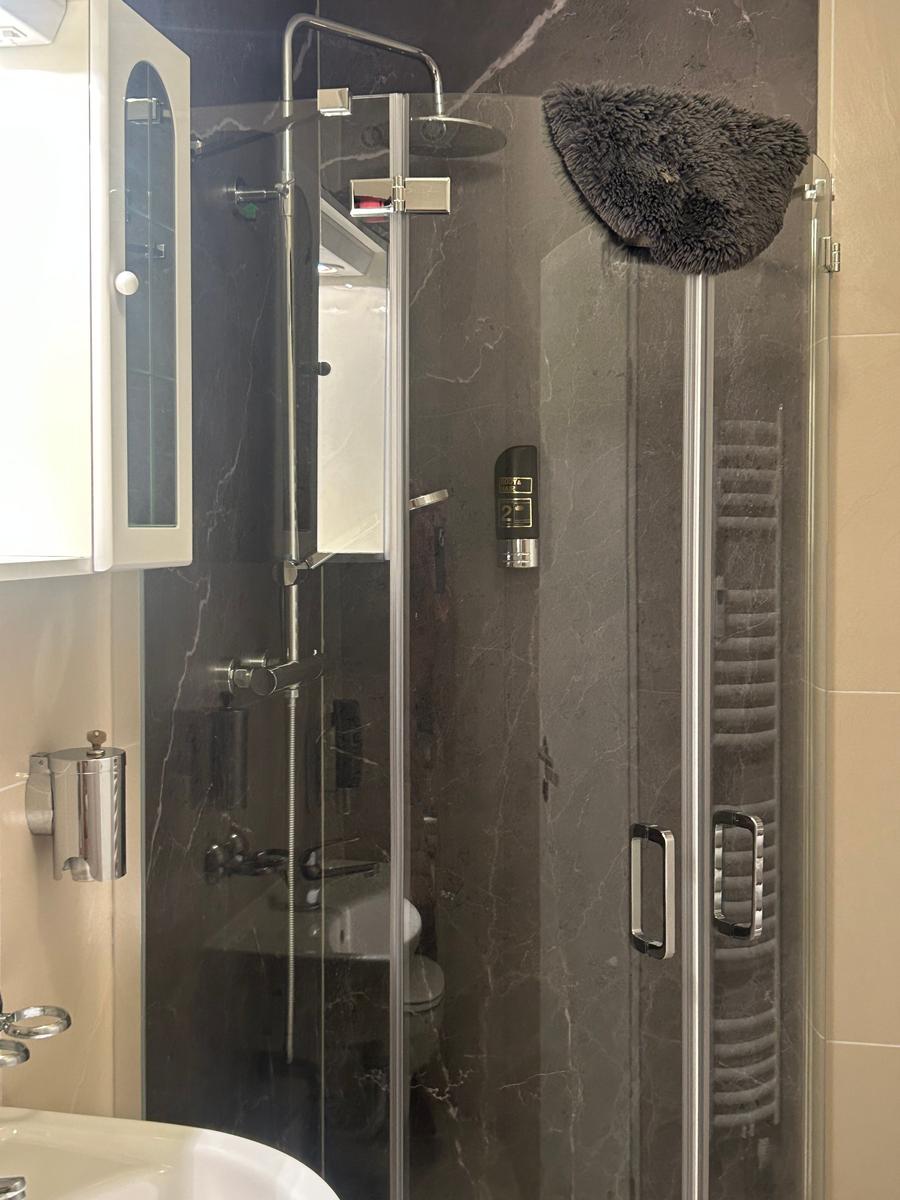 Duschkabine mit Glaswand, Handtuchhalter und Duschbrause.