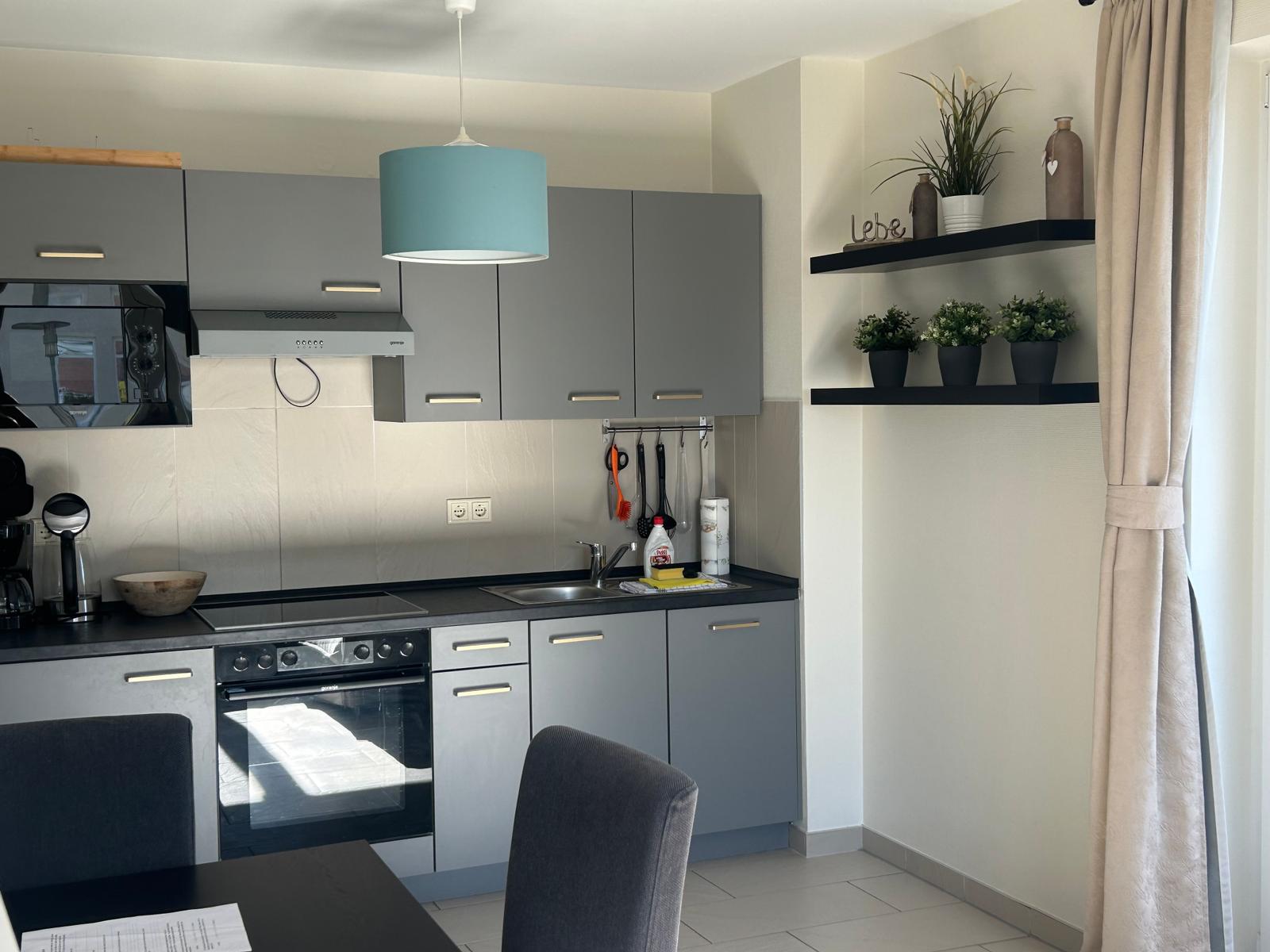 Küche mit grauen Schränken, Dunstabzug und Arbeitsplatte.