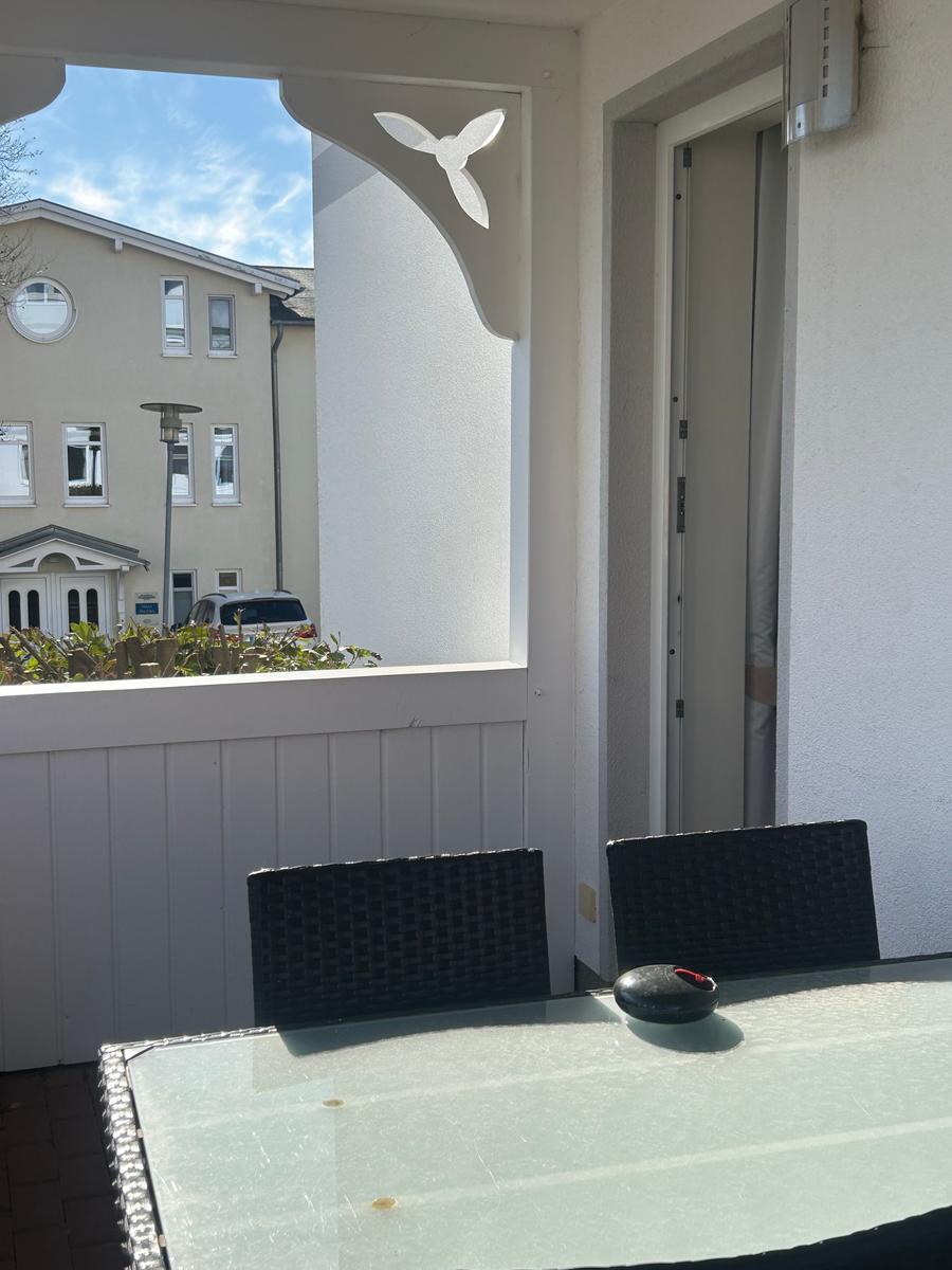 Terrasse mit Tisch und Stühlen, Blick auf Nachbarhaus und Garten.