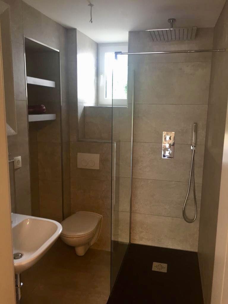 Dusche mit Duschbrause, Toilette und Waschbecken in moderner Badezimmerausstattung.