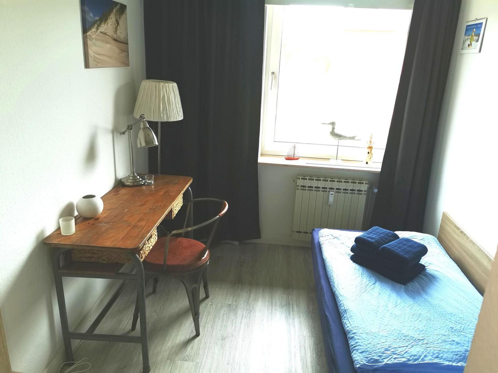 Schlafzimmer mit Bett, Schreibtisch und Fenster