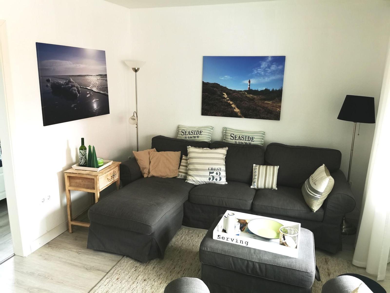 Ein Wohnzimmer mit einem dunklen Sofa, zwei Wandbildern und einem Couchtisch.