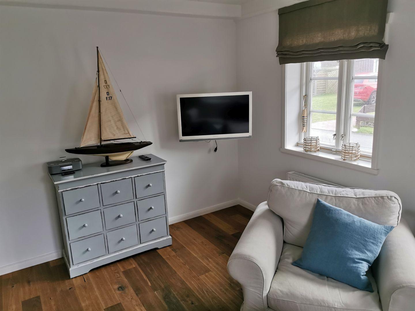 Ein Wohnbereich mit Sofa, Fernseher und Modellboot.