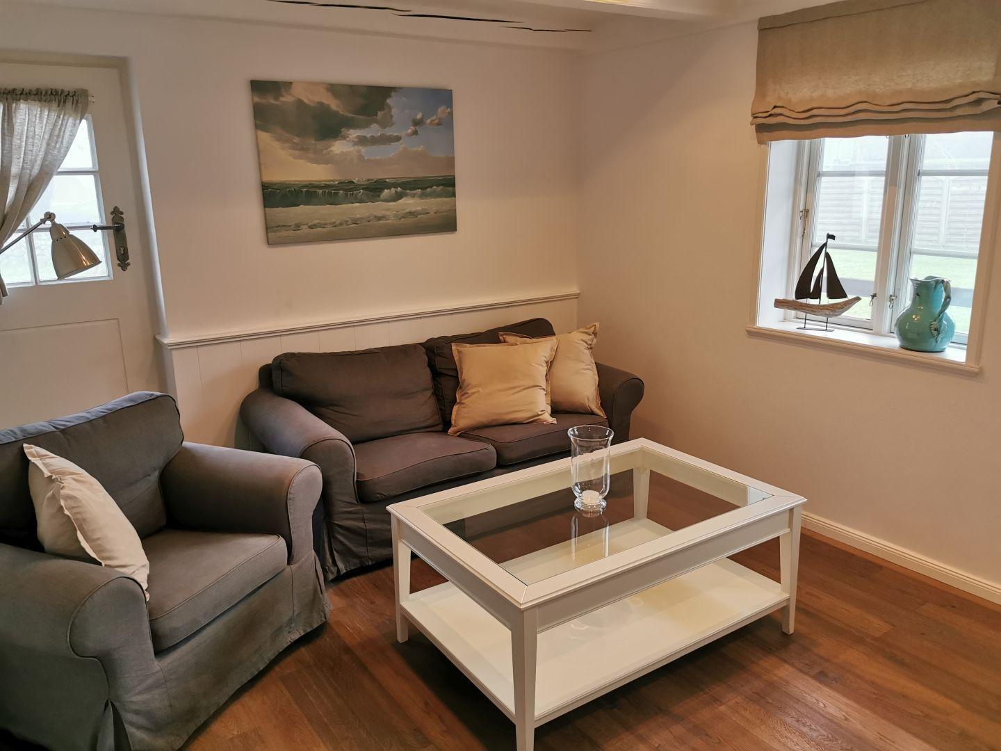 Wohnzimmer mit Sofa, Sessel, Glas-Tisch und Wandbild